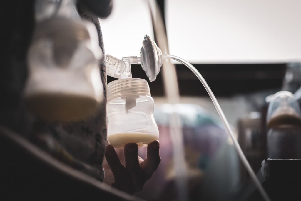 mother pumping her breast with automatic breast pump and sunlight evening. mother's day, suckling, infant, motherhood, innocence concepts